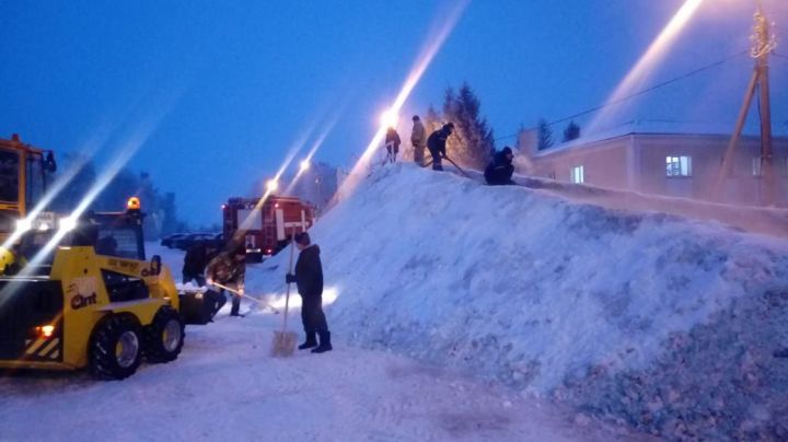 Работники коммунальной службы и пожарные трудятся над строительством ледяной горки